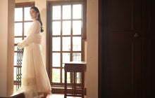 A woman in ivory by a tall window, from the Vasl film