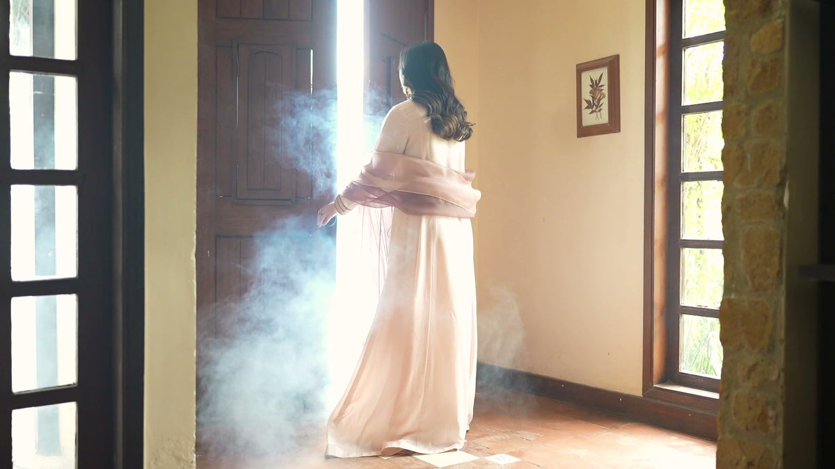 A woman in ivory at a sunlit doorway, from the Vasl campaign film